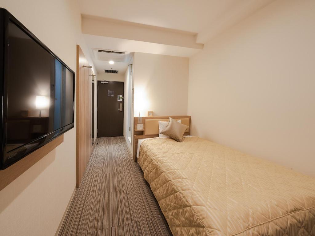 a bedroom with a bed and a flat screen tv at UNIZO INN Osaka Kitahama in Osaka