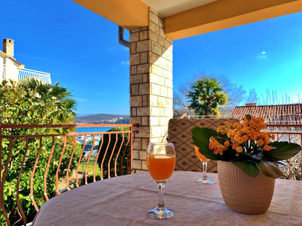 un tavolo con due bicchieri da vino e un vaso di fiori di Apartments Nevenka K. a Čižići