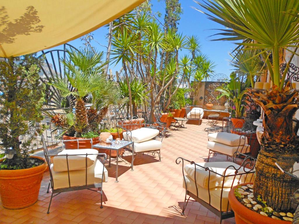 un patio con tavoli, sedie e palme di Apartment Giardino delle Palme by Interhome a Palermo