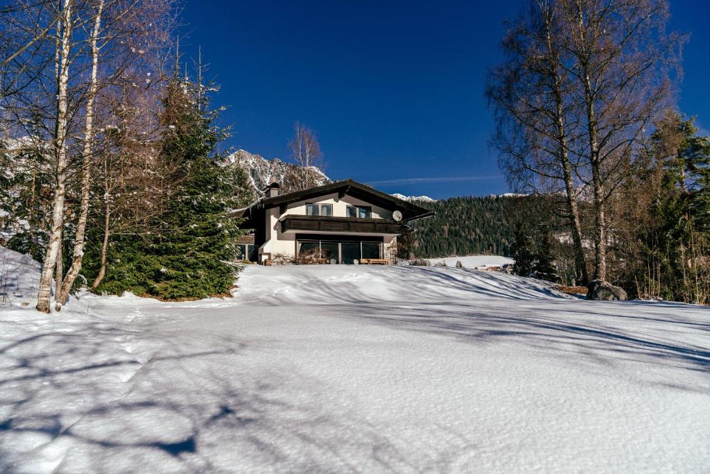 una casa en una carretera cubierta de nieve frente a una casa en Landhaus Blaubeerhügel, en Ramsau am Dachstein