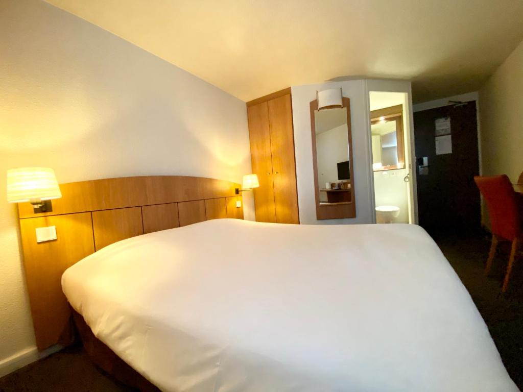a large white bed in a hotel room at Kyriad Montargis Amilly in Amilly