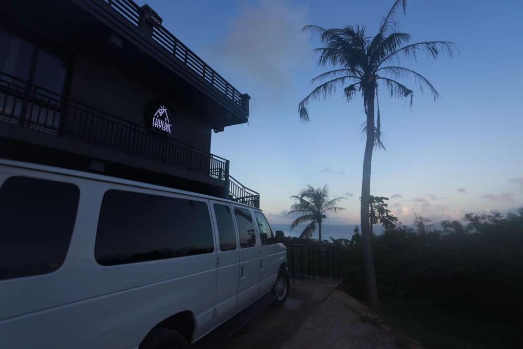 a white van parked next to a building with a palm tree at Saipan Skyline Designers Hotel in Saipan
