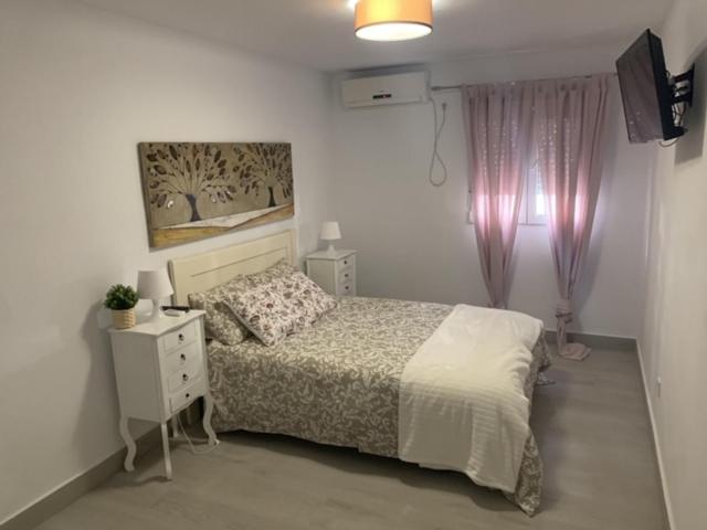 a bedroom with a bed and a dresser and a television at WISH SUITE NIEBLA DE SEVILLA in Seville