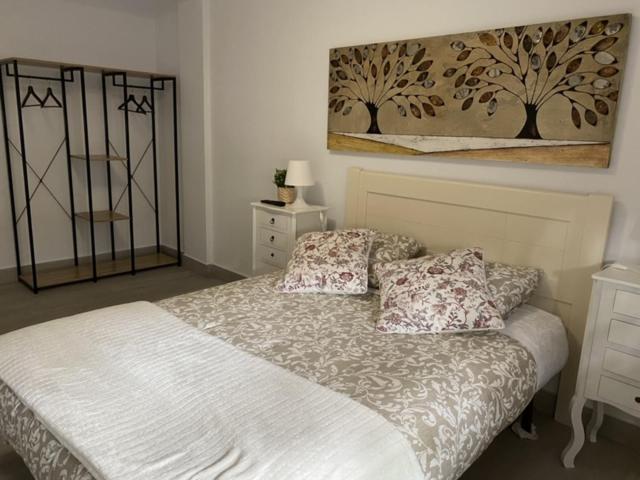 a bedroom with a bed and a painting on the wall at WISH SUITE NIEBLA DE SEVILLA in Seville