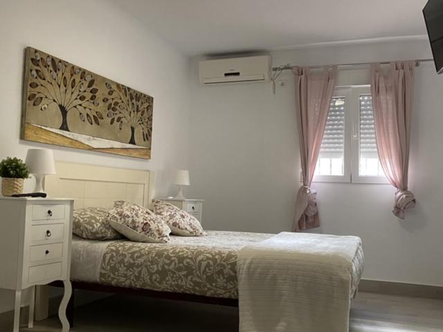 a white bedroom with a bed and a window at WISH SUITE NIEBLA DE SEVILLA in Seville