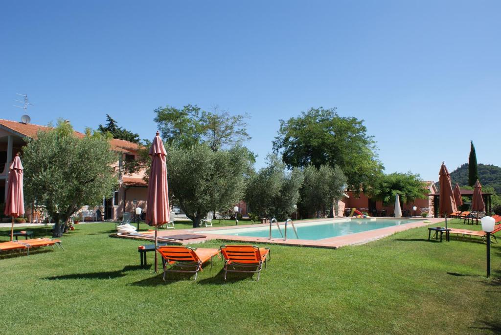 una piscina con sillas y sombrillas en el césped en Agriturismo La Siesta, en Marsiliana