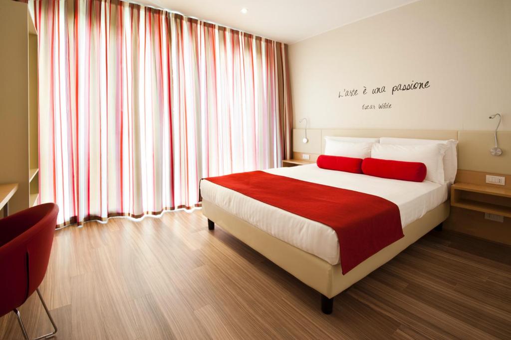 a bedroom with a bed with two red pillows at UNAHOTELS Le Terrazze Treviso Hotel & Residence in Villorba