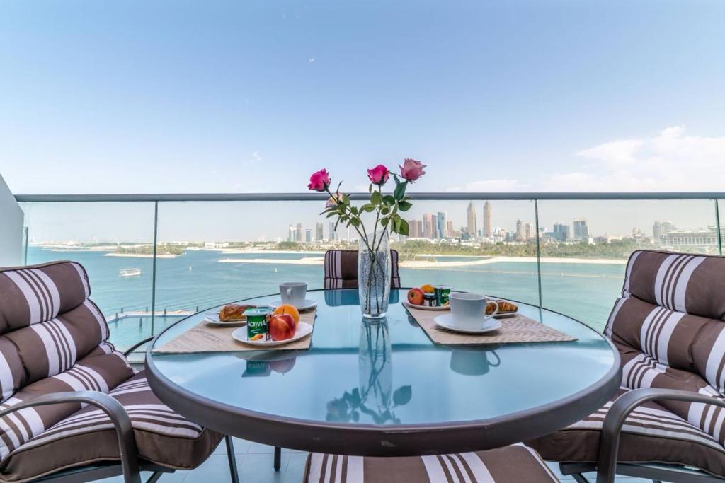 a glass table with a vase of flowers on a balcony at Holiday Apartment in Palm Jumeirah with Beach Access in Dubai