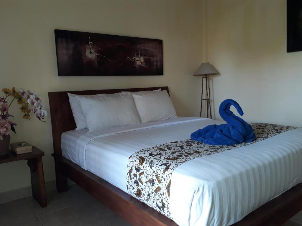 ein Schlafzimmer mit einem Bett und einem blauen Handtuch darauf in der Unterkunft Adi House Homestay in Ubud