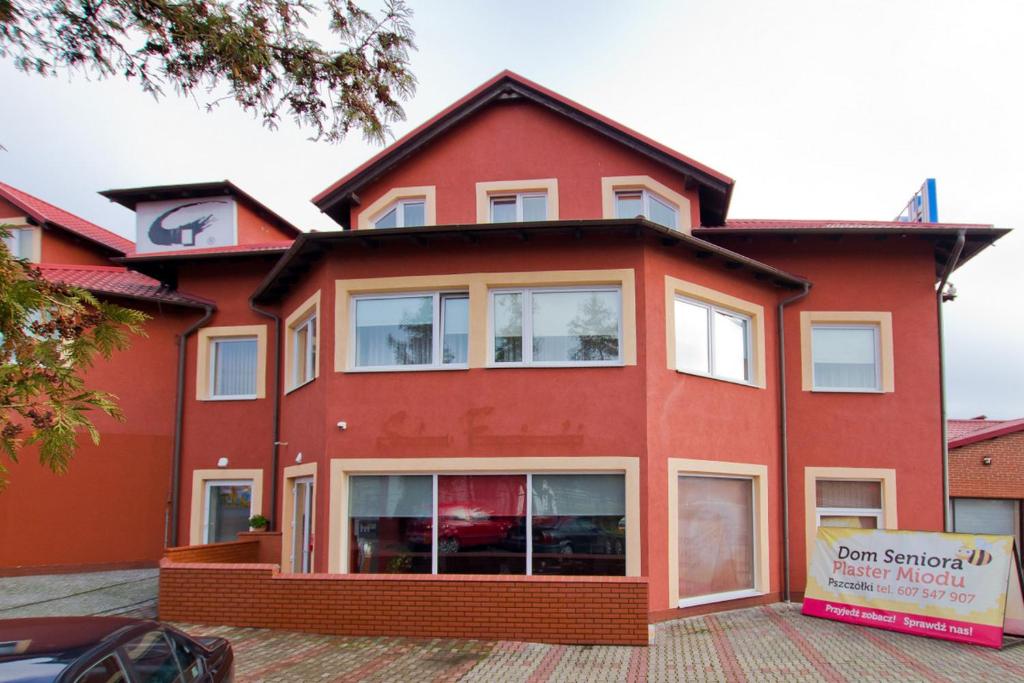 een rood huis met een bord ervoor bij Hotel Gregor in Pszczółki