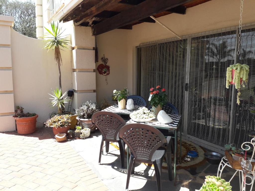 een patio met een tafel, stoelen en planten bij At The View B&B in Roodepoort