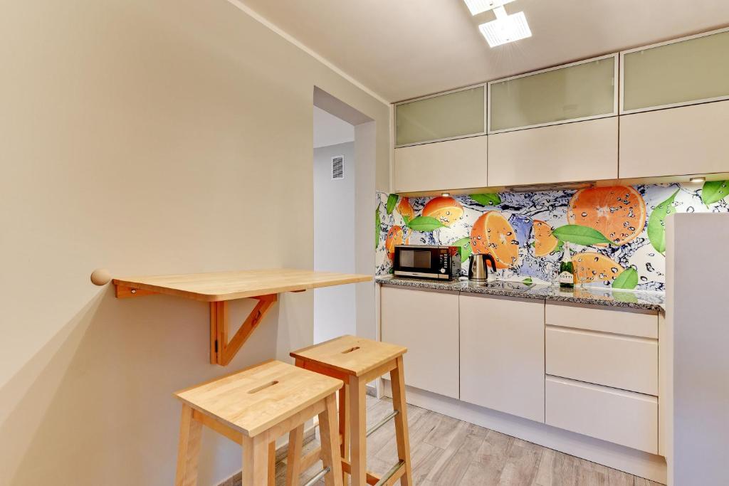 a kitchen with white cabinets and wooden stools at Villa Arkodes in Gdańsk
