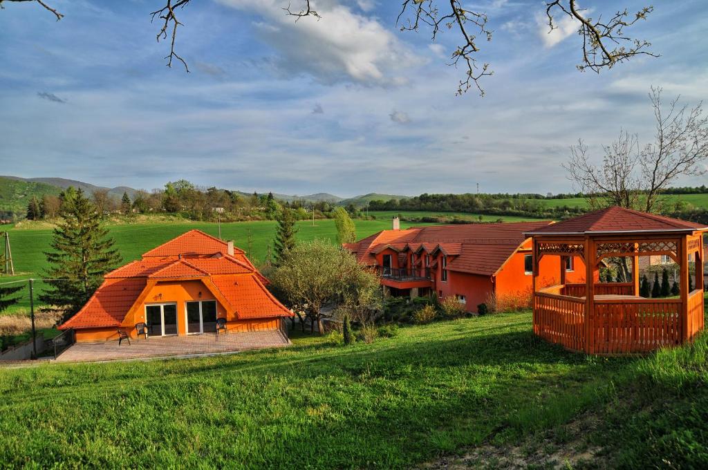 ein Haus mit einem orangenen Dach auf einem grünen Feld in der Unterkunft Harmónia Wellness Villa in Szilvásvárad