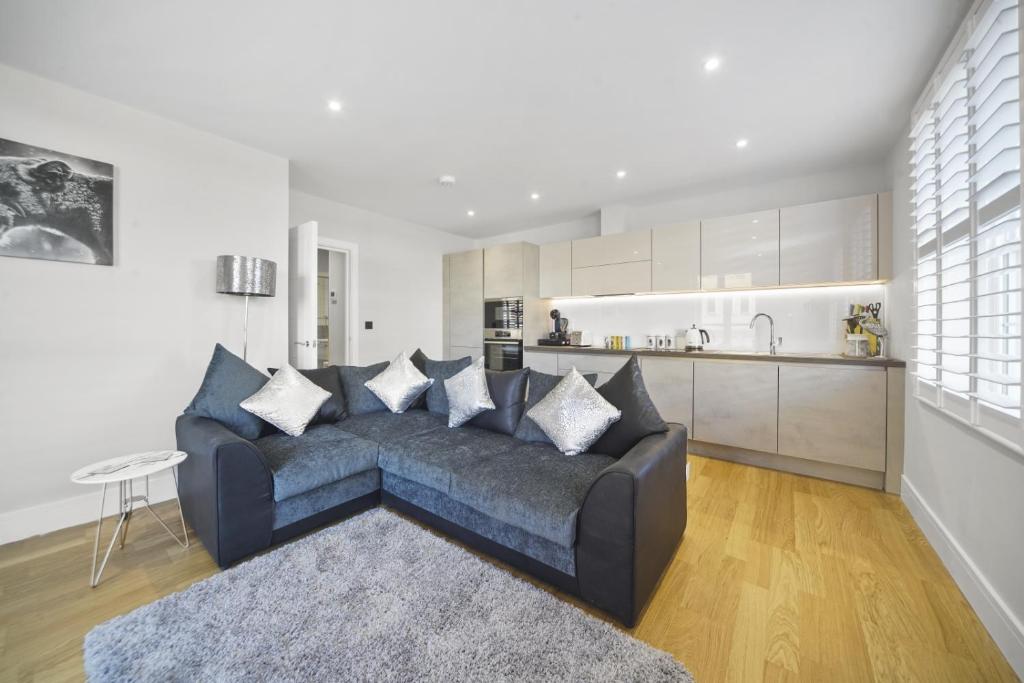 a living room with a couch and a kitchen at Flat 1 Bridge House in Staines