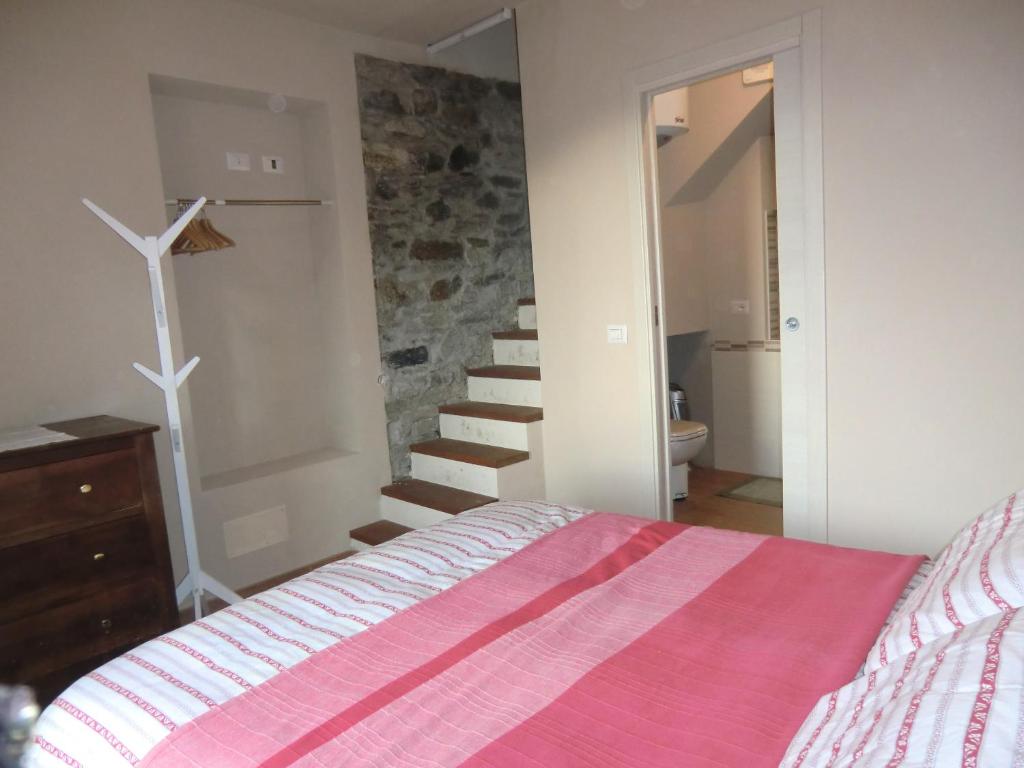 a bedroom with a bed and a stone staircase at LA PICCIONAIA in Varallo