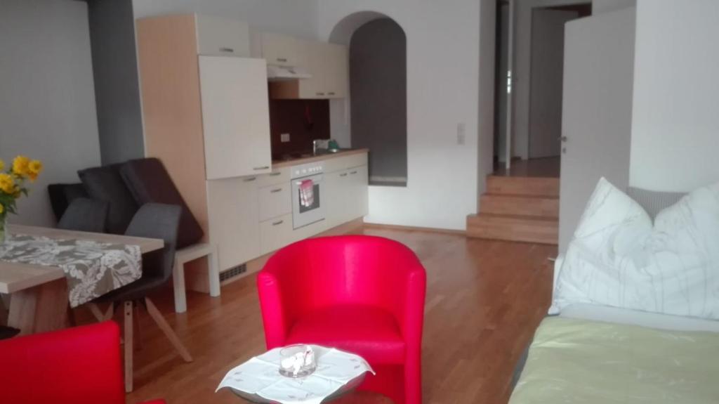 ein Wohnzimmer mit einem roten Stuhl und einem Tisch in der Unterkunft Ferienwohnung Murtal in Sankt Lorenzen bei Knittelfeld