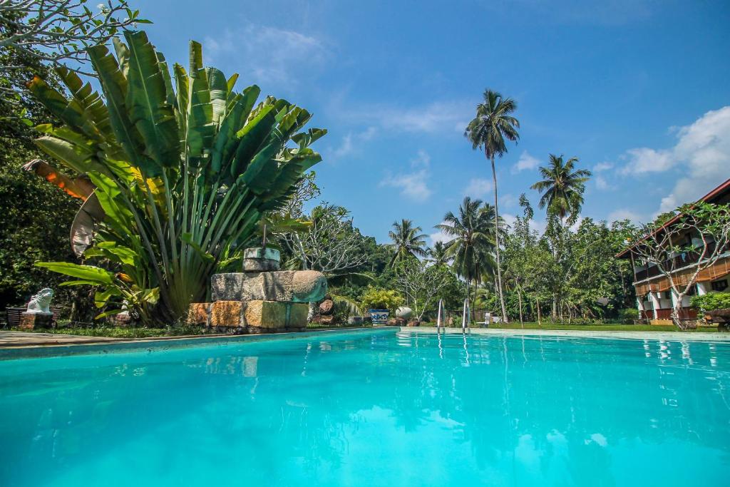 a swimming pool in front of a resort with palm trees at Nooit Gedacht Heritage Hotel (Original Dutch Governors House) in Unawatuna