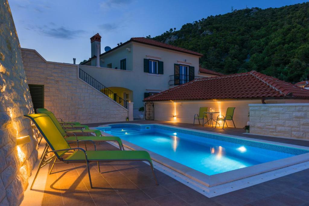 a swimming pool with chairs and a house at Villa Kogo in Hvar