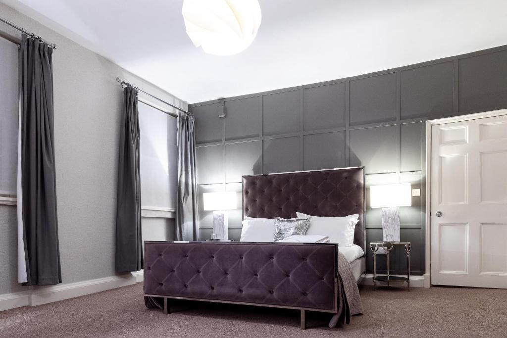 a bedroom with a bed with a large black headboard at The City Rooms in Leicester