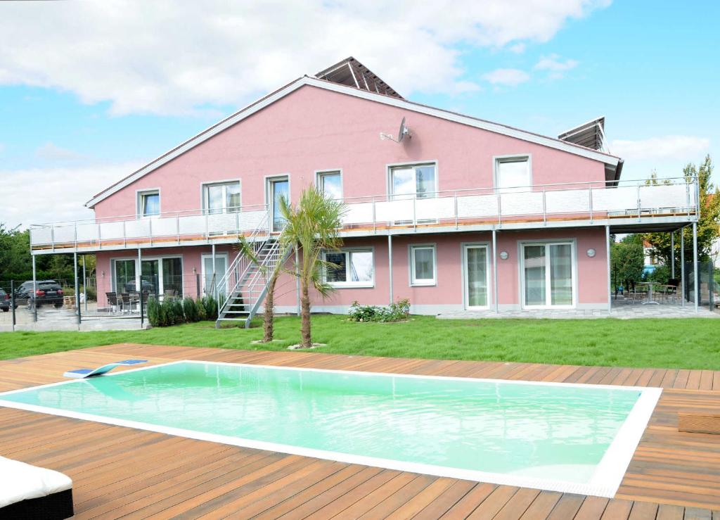 una casa rosa con piscina frente a ella en Caseti 5_ Ferienwohnungen _ Rothen, en Oberdachstetten