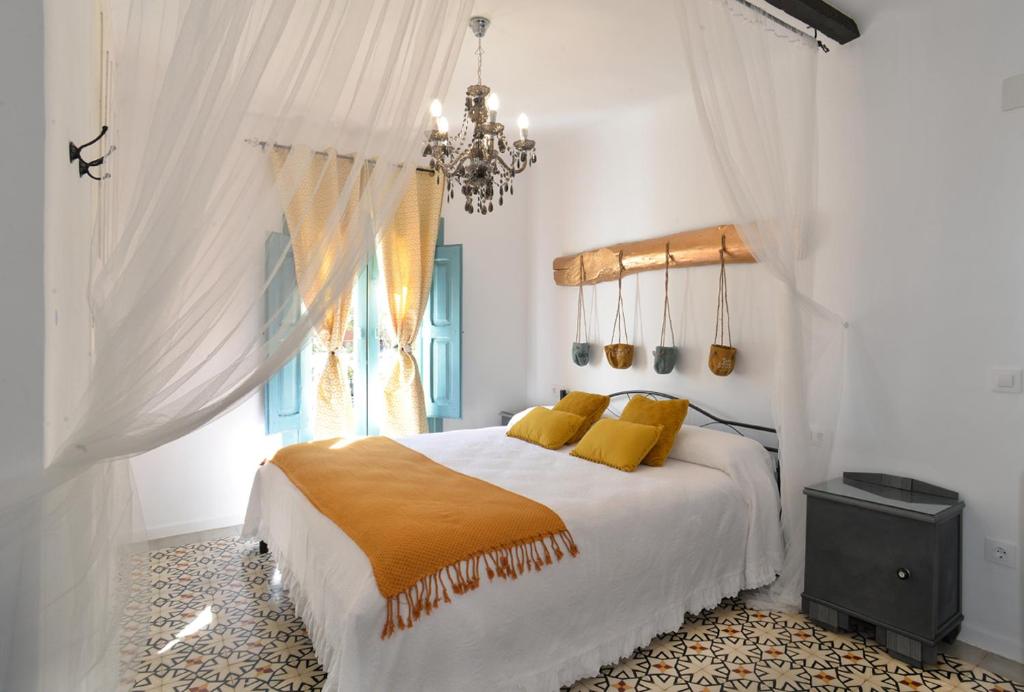 een slaapkamer met een bed met gele kussens en een kroonluchter bij La Boutique in Nuévalos