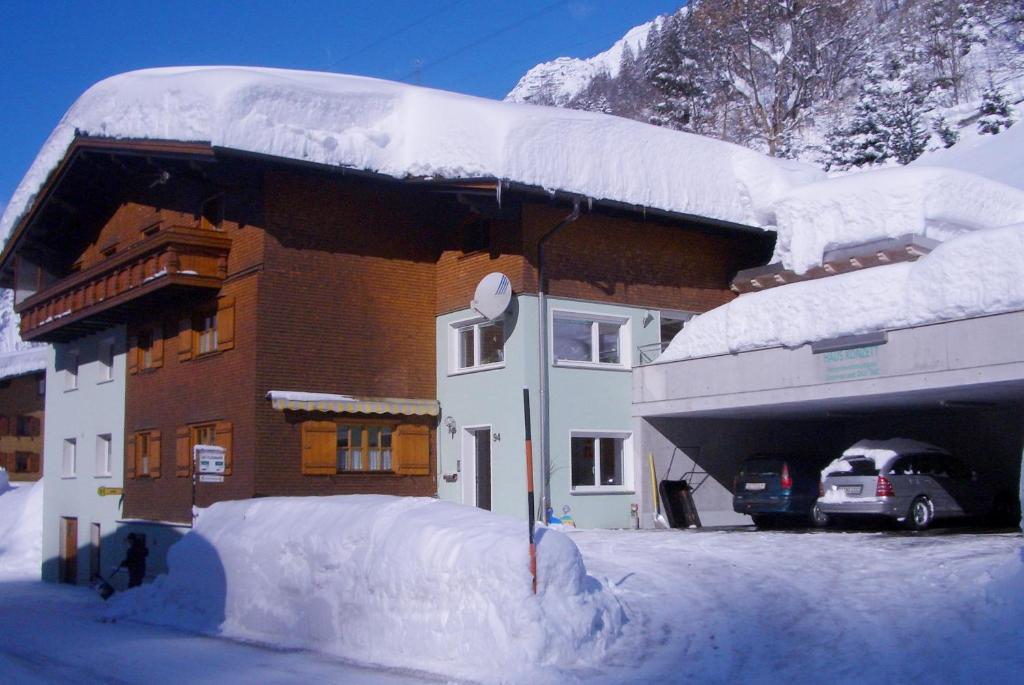 ein schneebedecktes Gebäude mit einem Auto auf einem Parkplatz in der Unterkunft Haus Konzett in Klösterle am Arlberg