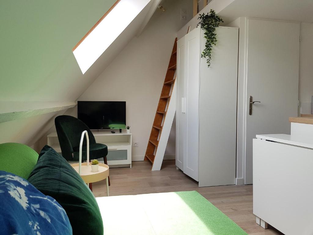 a living room with a green couch and a staircase at Le Fleury - Studio calme proche de Rouen in Déville-lès-Rouen