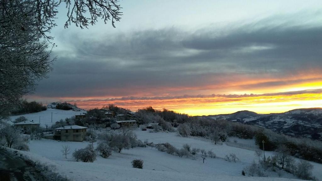 einen winterlichen Sonnenuntergang über einem schneebedeckten Feld mit Häusern in der Unterkunft Albergo Filietto in Bobbio