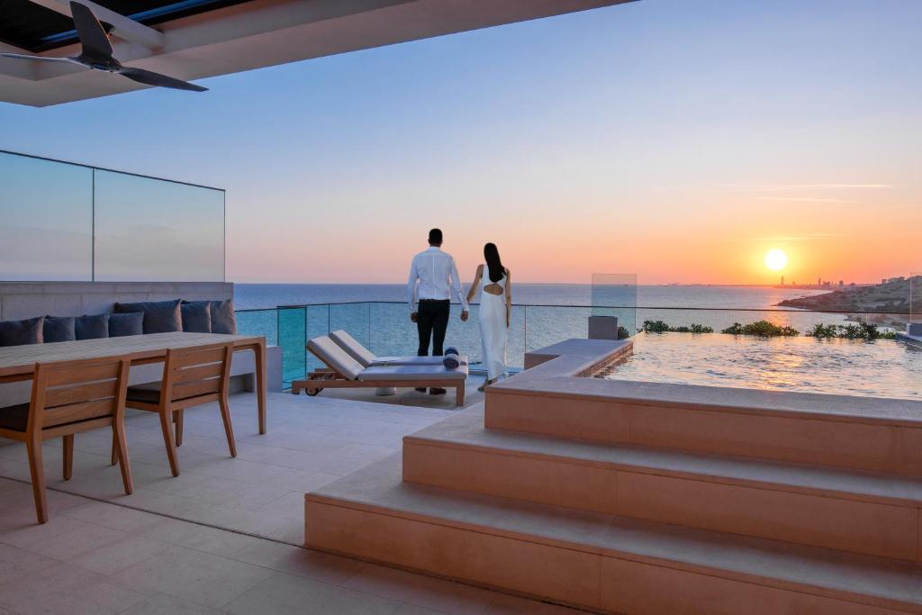a couple standing on the balcony of a house watching the sunset at Amara - Sea Your Only View™ in Limassol