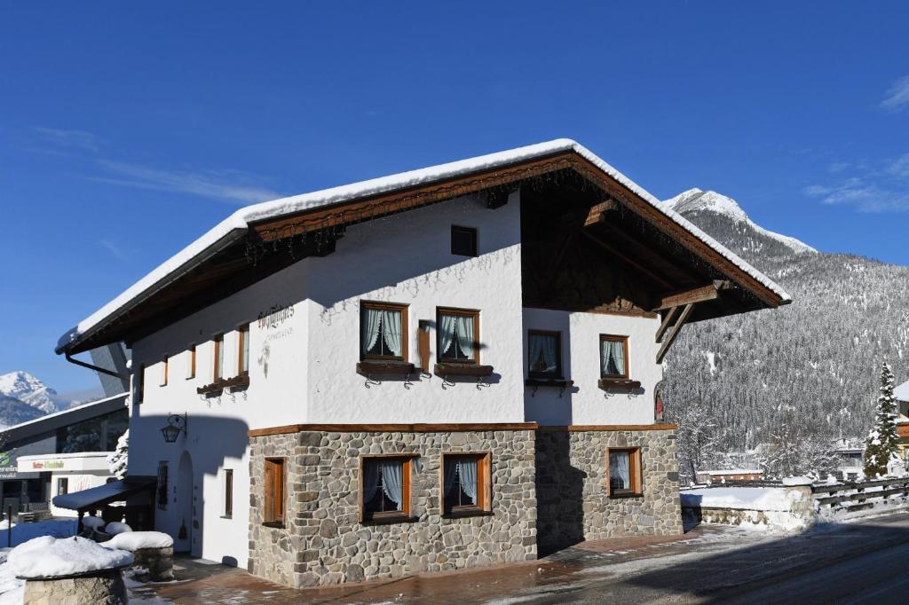 ein Gebäude mit einem schneebedeckten Berg im Hintergrund in der Unterkunft Holzschnitzers Appartements in Ehrwald