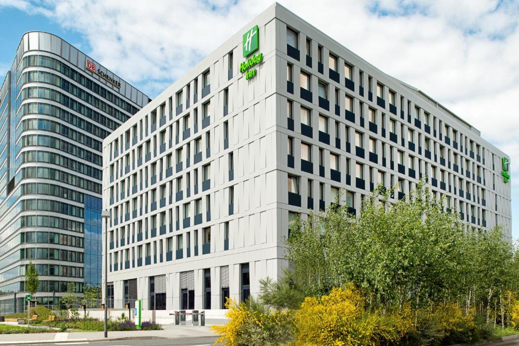 a tall white building with a green sign on it at Holiday Inn Frankfurt Airport, an IHG Hotel in Frankfurt