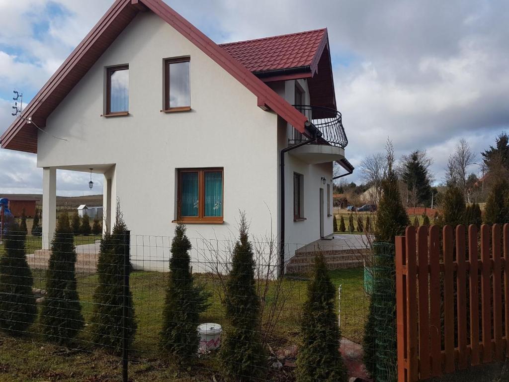 een wit huis met een hek in een tuin bij DOM NA MAZURACH in Przerwanki