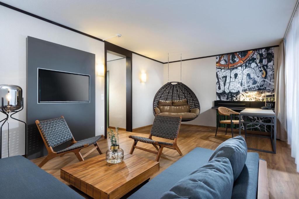 a living room with a couch and chairs and a tv at Seminaris Hotel Lüneburg in Lüneburg