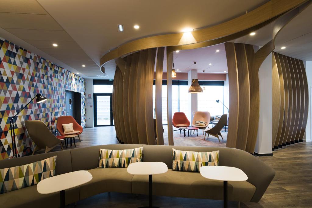 a lobby with a couch and tables and chairs at Holiday Inn Express - Paris - CDG Airport by IHG in Roissy-en-France