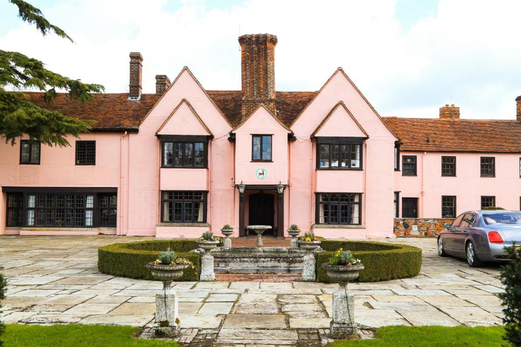 una casa rosa con un coche aparcado delante de ella en Little Easton Manor en Great Easton