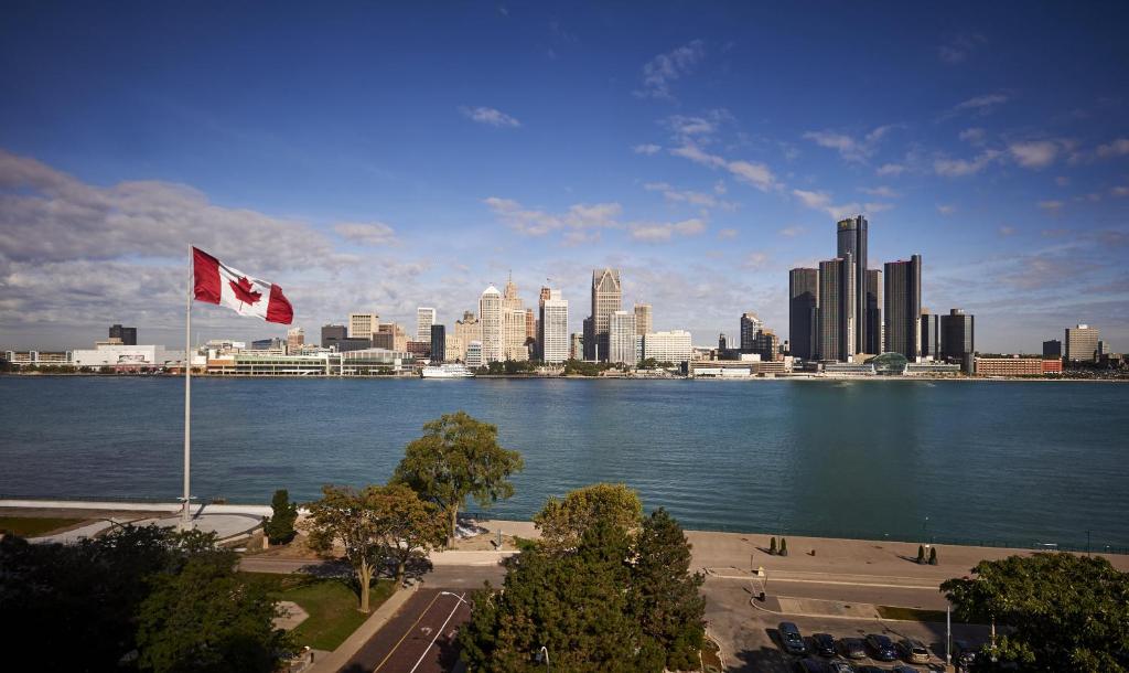a canadian flag flying over the water with a city at Holiday Inn Express Windsor Waterfront by IHG in Windsor
