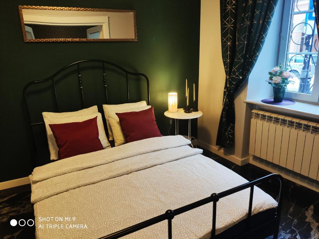 Schlafzimmer mit einem Bett mit roten Kissen und einem Spiegel in der Unterkunft Apartament Nina in Warschau