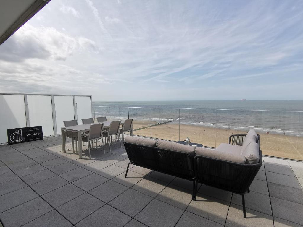 a balcony with a table and chairs and a view of the beach at Unieke Penthouse bij Brugge in Blankenberge