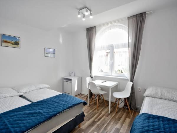 1 dormitorio con 2 camas, escritorio y ventana en Przy Plaży en Karwia