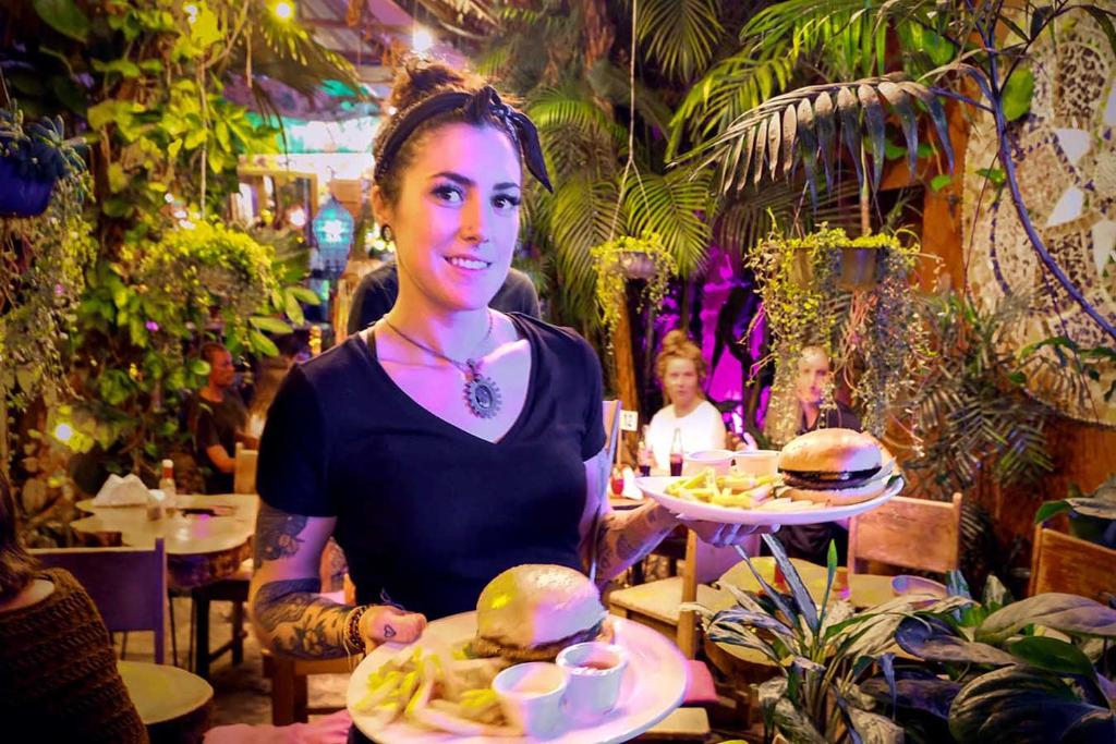 a woman sitting at a table with plates of food at Los Amigos Hostel in Flores