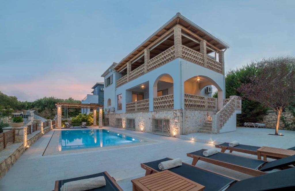 een villa met een zwembad en tuinmeubilair bij Villa Daphne in Tsilivi