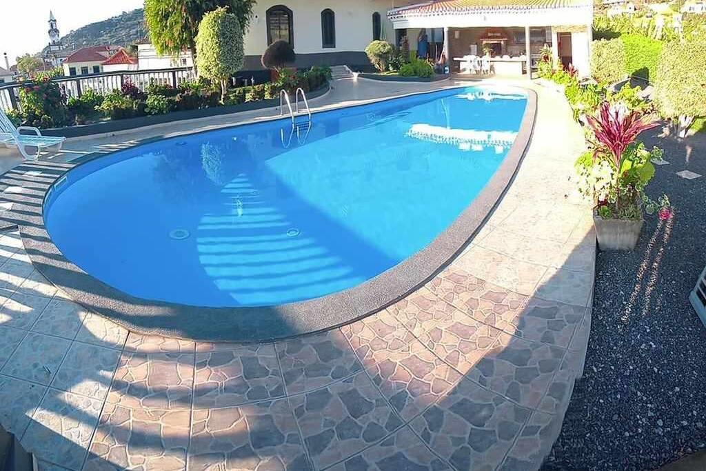 een groot zwembad met blauw water in een tuin bij Arcos Grands Suites with enormous and private pool. in Arco da Calheta