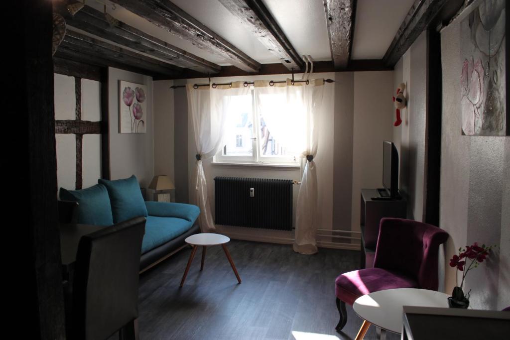 sala de estar con sofá azul y ventana en Appartement les Violettes, en Colmar