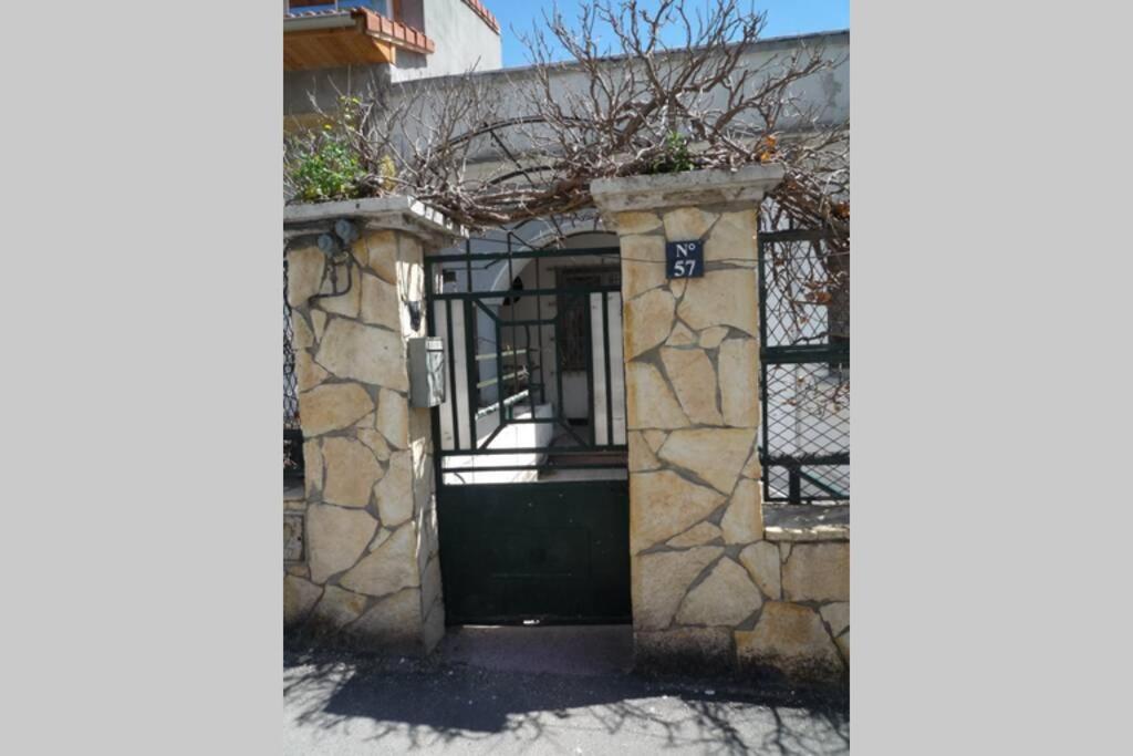 una casa con una puerta verde y una pared de piedra en SuperF2+2020 en LʼAgha