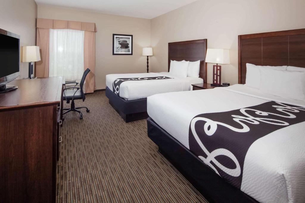 a hotel room with two beds and a flat screen tv at La Quinta by Wyndham Inglewood in Inglewood