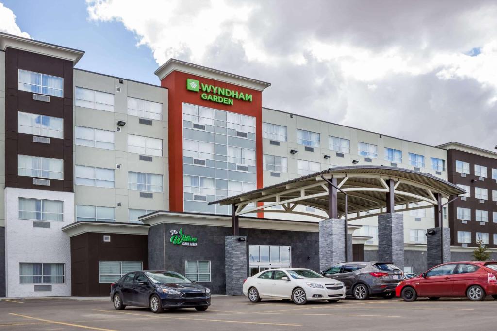 ein Gebäude mit Autos auf einem Parkplatz in der Unterkunft Wyndham Garden Edmonton Airport in Leduc