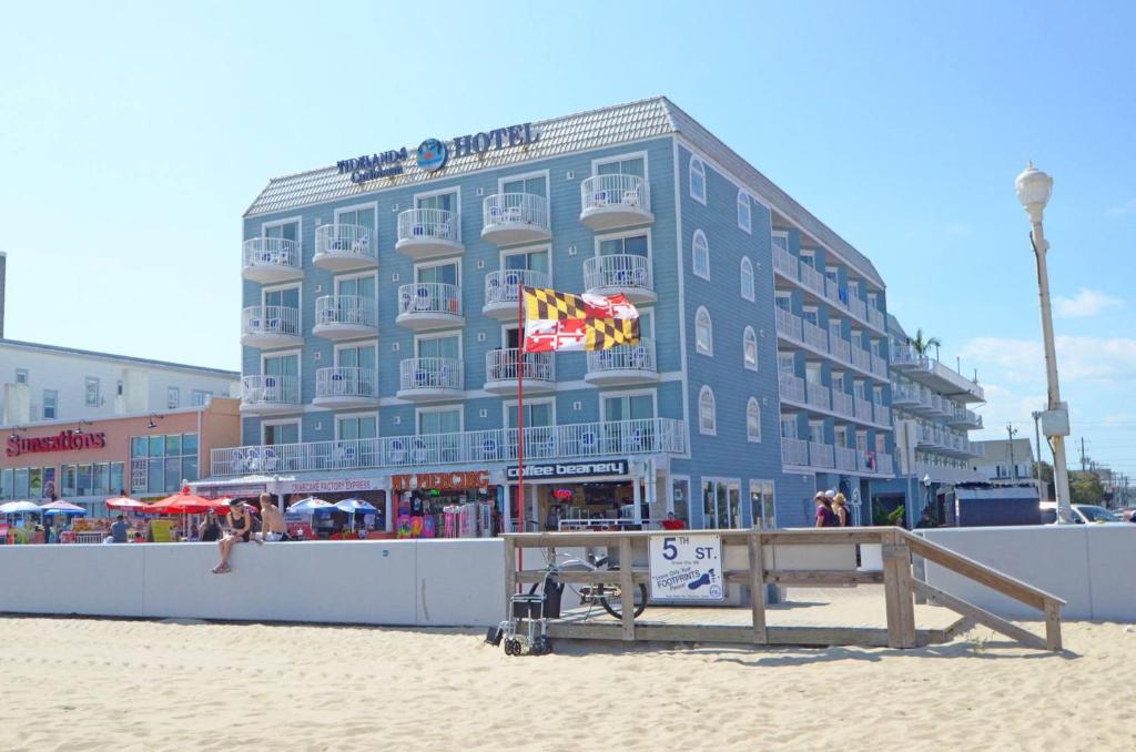 un gran edificio azul en la playa junto a la arena en Tidelands Caribbean Boardwalk Hotel and Suites, en Ocean City