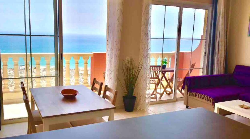 a living room with a table and a view of the ocean at APARTAMENTO ANA in Costa Calma