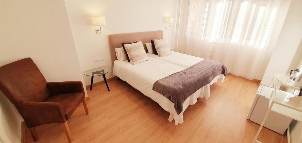 1 dormitorio pequeño con 1 cama y 1 silla en Fan Rooms Gálvez, en Málaga