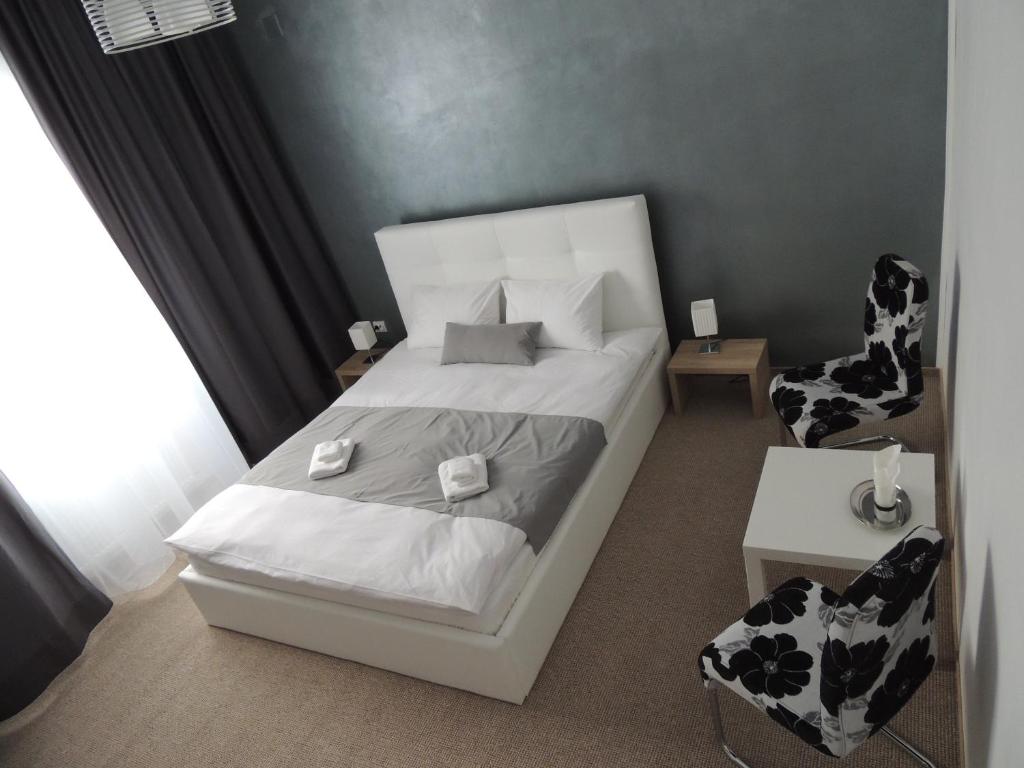 a small bedroom with a white bed and a chair at Pensiunea Sada in Cluj-Napoca